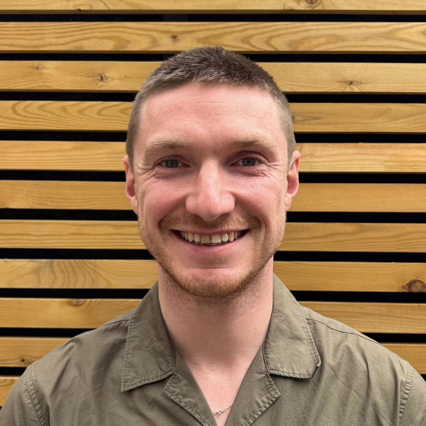Head and shoulders of Gareth Hughes in front of wood panelled wall.